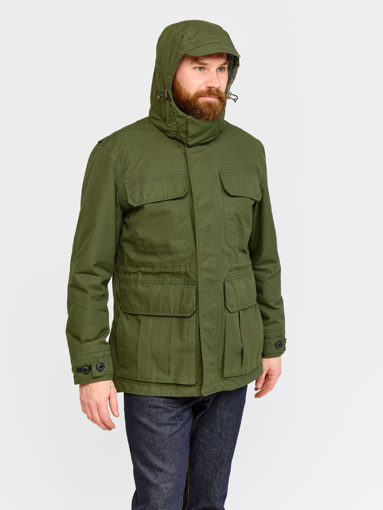 Model wearing FRAHM Ventile Thermal Field 2026 Military Green in studio with hood up