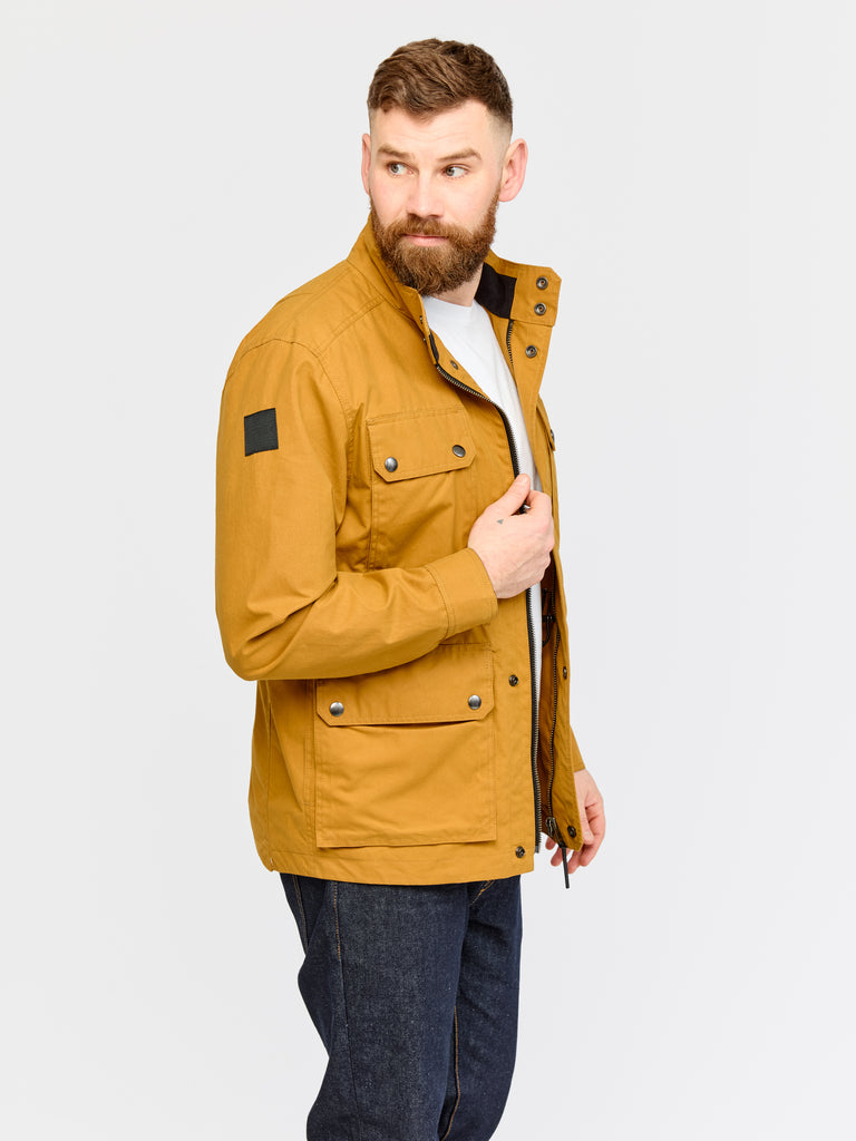 Side on view of model wearing FRAHM Waxed Classic Field Jacket 2026 in Honey Tan