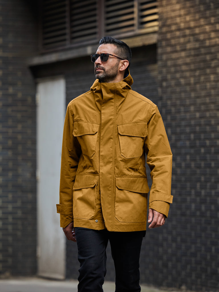 Model wearing FRAHM Waxed Hooded Field Coat in Honey Tan outdoor
