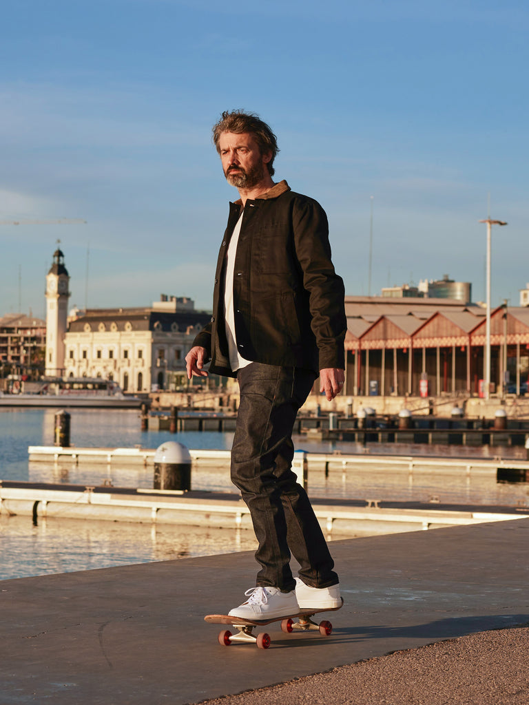 Model skateboarding wearing FRAHM Heavy Twill Deck Jacket 2027 in Black