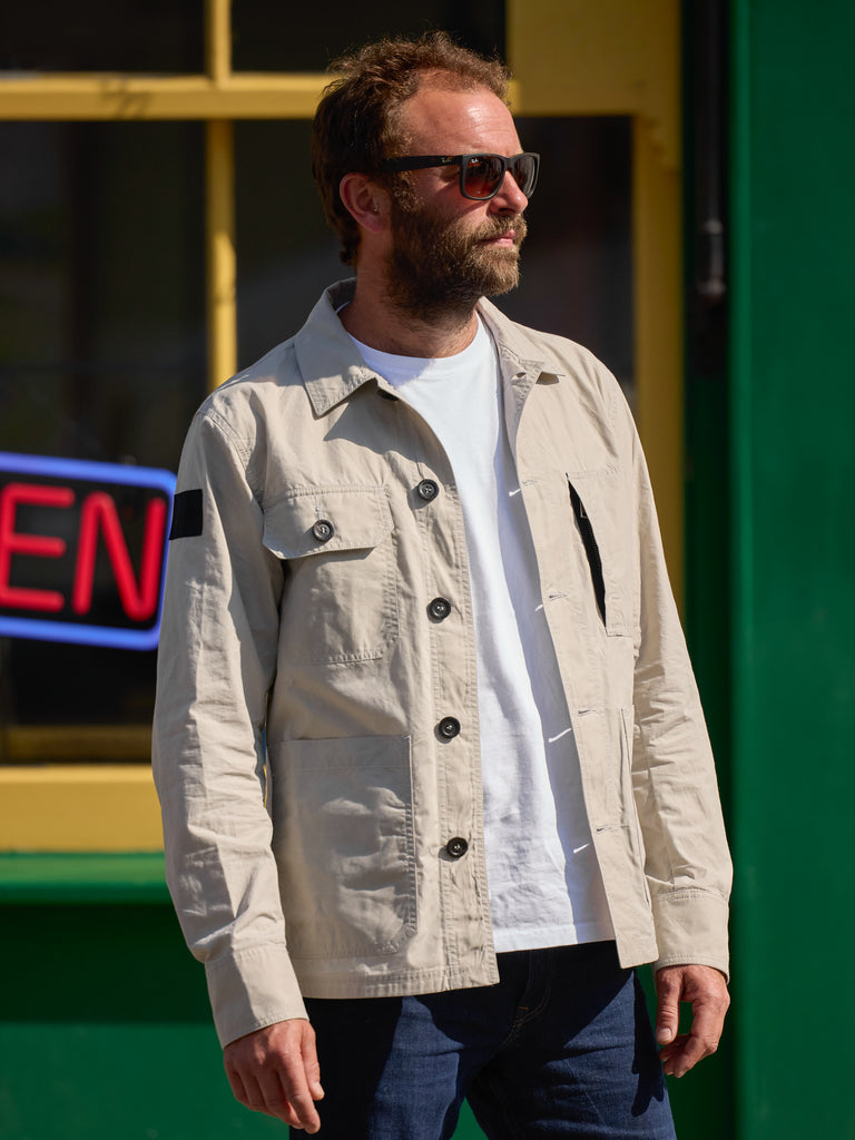 Model wearing FRAHM Waxed Lightweight Workers Jacket 2027 Bath Stone outdoors