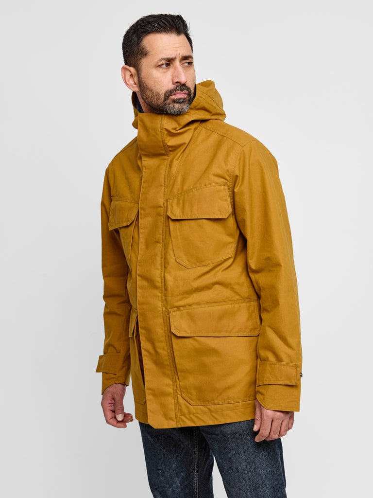 Model wearing FRAHM Waxed Hooded Field Coat in Honey Tan indoor front view