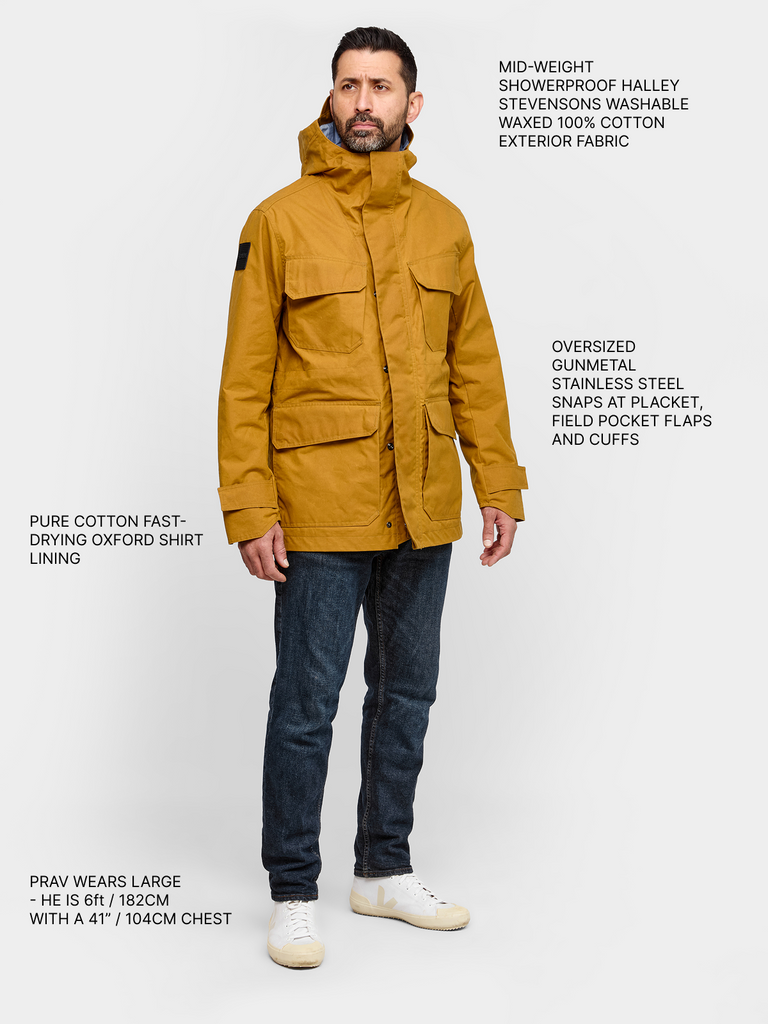 Model wearing FRAHM Waxed Hooded Field Coat in Honey Tan full body with product details